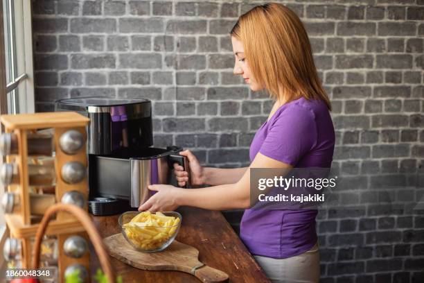 belle adolescente utilisant une friteuse à air dans la cuisine - vent photos et images de collection