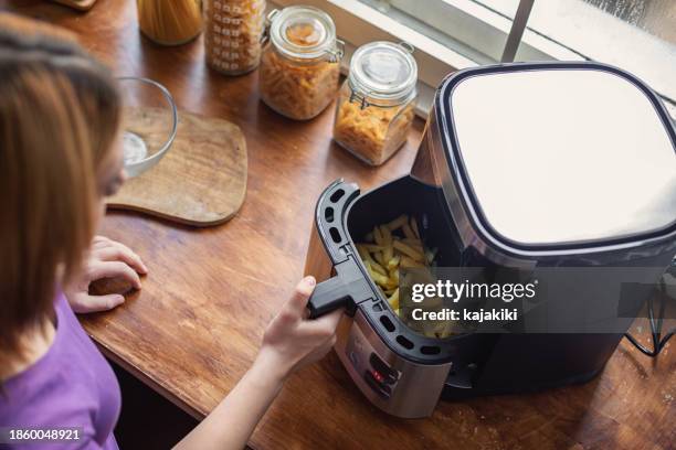 schönes teenager-mädchen mit einer heißluftfritteuse in der küche - fritteuse stock-fotos und bilder