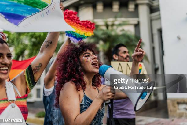 lesbische junge frau schreit am megaphon während einer sozialen bewegung, die im freien protestiert - defend your rights stock-fotos und bilder