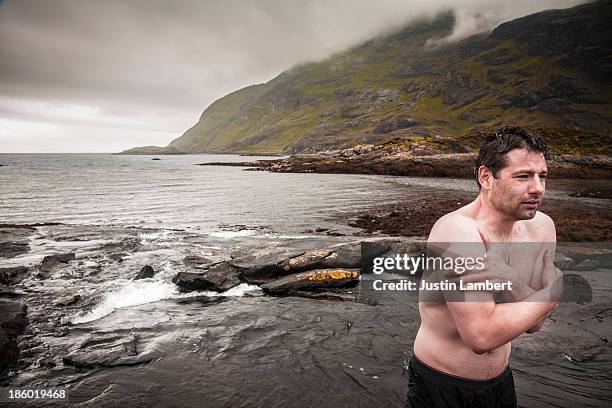 man stands shivering after wild swim in scotland - shaking stock pictures, royalty-free photos & images