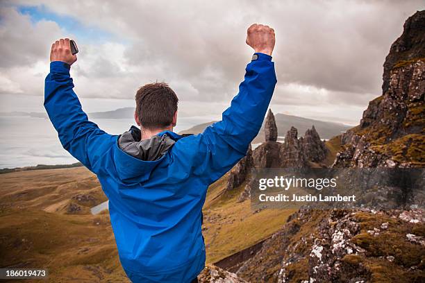 man cheers after reaching top of viewpoint - old man of storr stock pictures, royalty-free photos & images