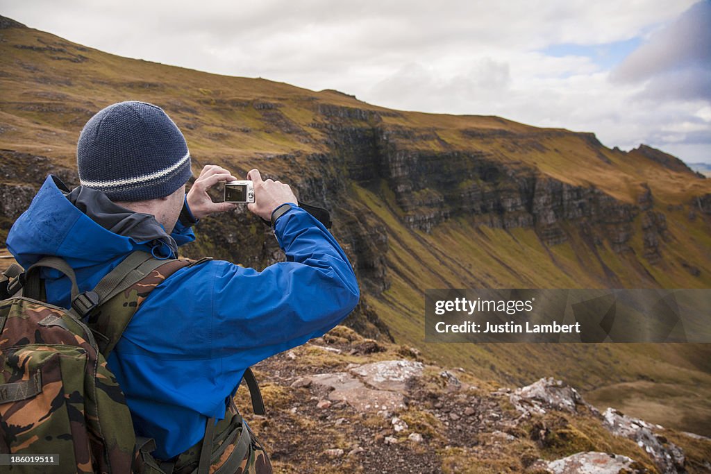 MAN TAKES PICTURE OF LANDSCAPE IN SKYE, SCOTLAND
