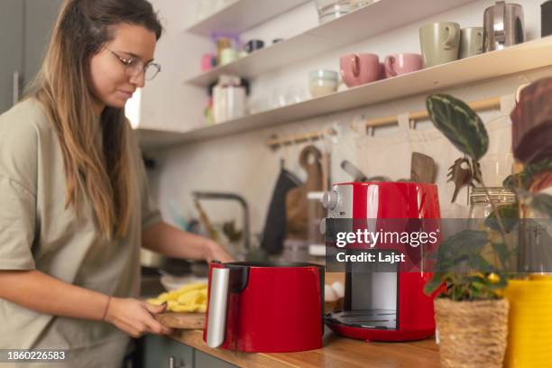 a beautiful woman preparing a meal using an air fryer - i was turning into a vegetable stock pictures, royalty-free photos & images