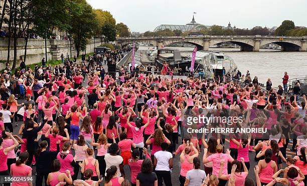 People take part in the "Dance in Pink" event, a free giant Zumba lesson, on October 27, 2013 on a bank of the Seine river in Paris, in support of...