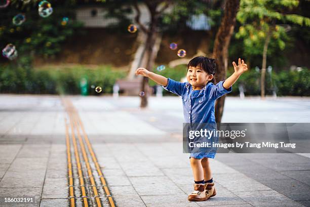 toddler girl catching bubbles joyfully in park - catching bubbles stock pictures, royalty-free photos & images