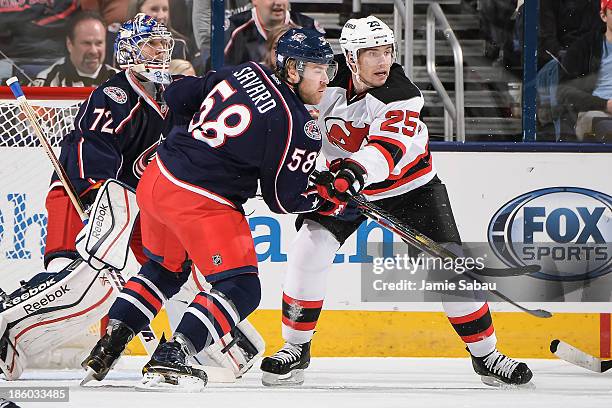 Rostislav Olesz of the New Jersey Devils and David Savard of the Columbus Blue Jackets battle for position in front of goaltender Sergei Bobrovsky of...