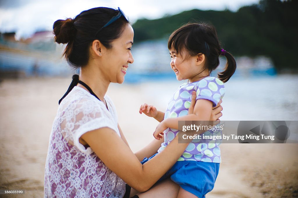 Young mom holding toddler on lap smiling joyfully