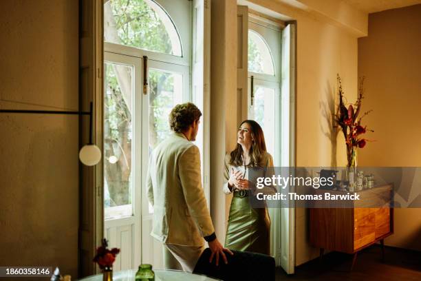 medium wide shot smiling woman and boyfriend relaxing in hotel suite - luxury hotel room stock pictures, royalty-free photos & images