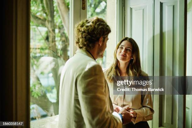 medium shot smiling couple standing at window in boutique hotel room - pareja de mediana edad fotografías e imágenes de stock