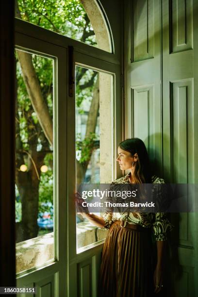 medium wide shot woman looking out hotel room window during vacation - luxury hotel room stock pictures, royalty-free photos & images