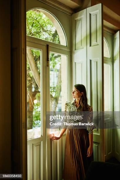 wide shot woman looking out window of hotel room during vacation - luxury hotel room stock pictures, royalty-free photos & images