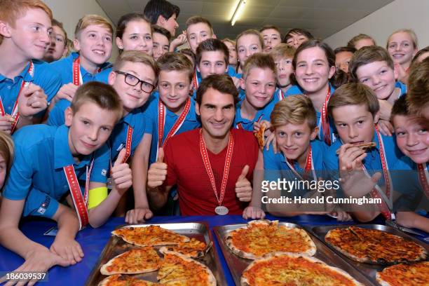Roger Federer of Switzerland hands out pizza as he celebrates with the ball boys the end of the Swiss Indoors ATP Tennis at St Jakobshalle on October...