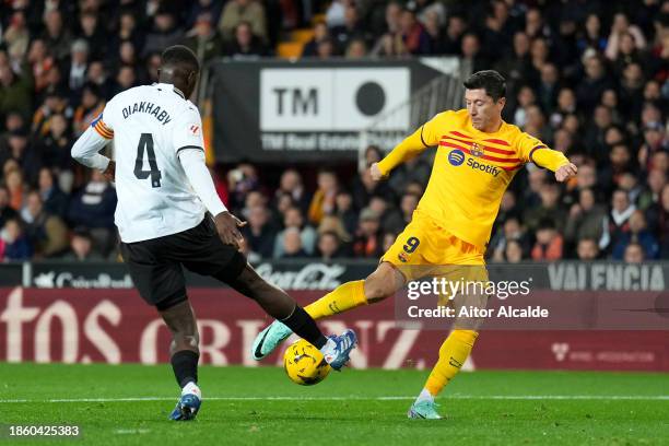 Robert Lewandowski of FC Barcelona shoots whilst under pressure from Mouctar Diakhaby of Valencia CF during the LaLiga EA Sports match between...