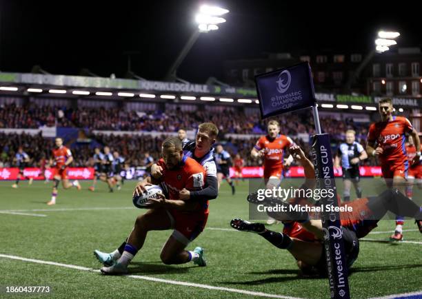 Ollie Lawrence of Bath Rugby scores their team's second try whilst under pressure from Cam Winnett of Cardiff Rugby during the Investec Champions Cup...