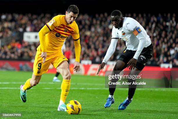 Robert Lewandowski of FC Barcelona runs with the ball whilst under pressure from Mouctar Diakhaby of Valencia CF during the LaLiga EA Sports match...