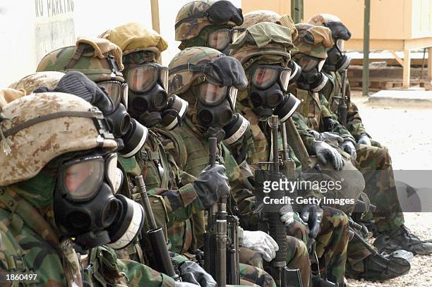 Soldiers with the first Marine Expeditionary Force wear chemical protective suits and gas masks in response to a chemical and biological attack alarm...