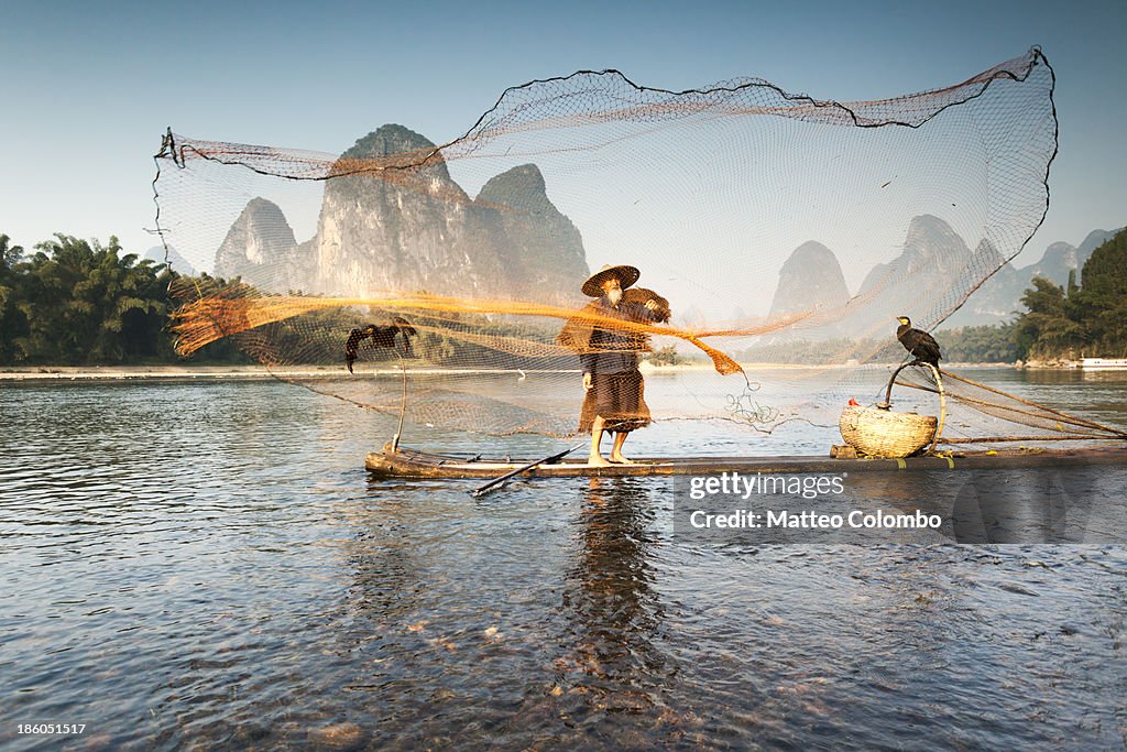 Fisherman on bamboo boat throwing the net