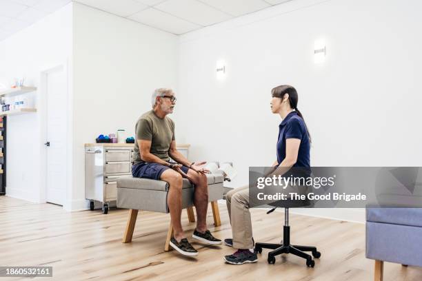 senior patient talking to female chiropractor at clinic - tabouret photos et images de collection