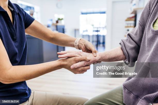 midsection of osteopath examining senior female patient's arm - kinésithérapie photos et images de collection