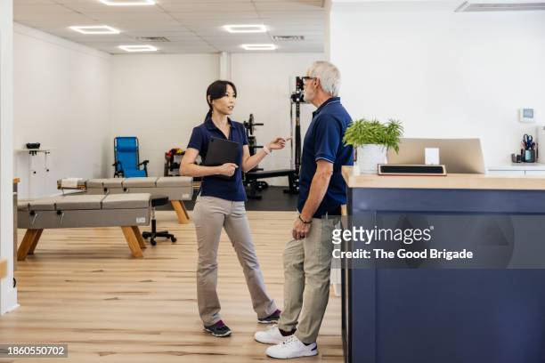 female and male osteopaths discussing at medical office - t shirt uniform stock pictures, royalty-free photos & images