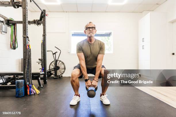 senior man using kettle ball at physical therapy - culturismo fotografías e imágenes de stock