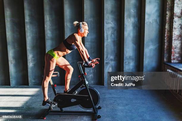 mid adult woman cycling in gym - training wheels stock pictures, royalty-free photos & images