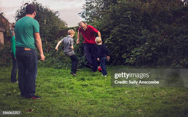 family playing football together in the garden - grandfather and grandson stock pictures, royalty-free photos & images