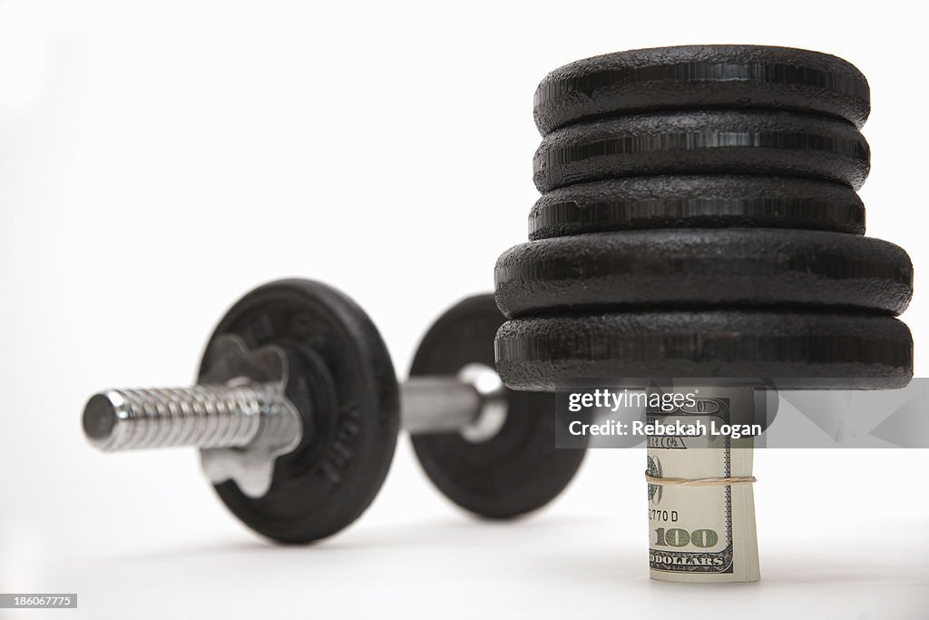 Roll of bank notes supporting weights.