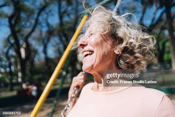 seniorin hat spaß auf schaukel im öffentlichen park - schaukel frau stock-fotos und bilder