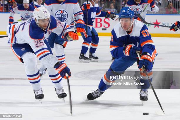 Casey Cizikas of the New York Islanders controls puck against Darnell Nurse of the Edmonton Oilers at UBS Arena on December 19, 2023 in Elmont, New...