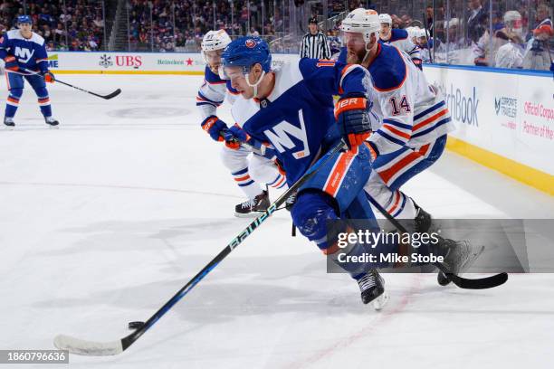 Julien Gauthier of the New York Islanders battles for puck against Mattias Ekholm of the Edmonton Oilers at UBS Arena on December 19, 2023 in Elmont,...