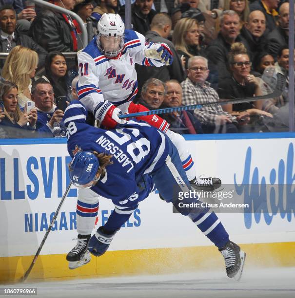 Barclay Goodrow of the New York Rangers slams into William Lagesson of the Toronto Maple Leafs during an NHL game at Scotiabank Arena on December 19,...