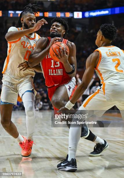 Illinois Fighting Illini forward Quincy Guerrier drives between Tennessee Volunteers forward Jonas Aidoo and Tennessee Volunteers guard Jordan Gainey...