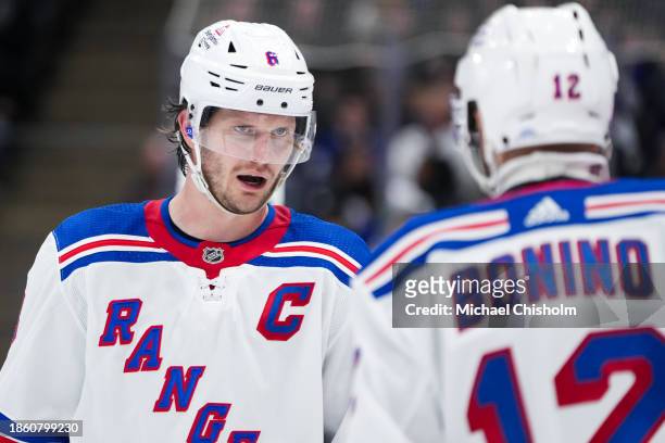 Jacob Trouba of the New York Rangers talks to Nick Bonino prior to a face off against the Toronto Maple Leafs at Scotiabank Arena on December 19,...