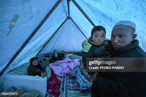 Earthquake survivors keep warm with blankets as they rest in a temporary shelter made of tarpaulin in Jishishan County in northwest China's Gansu...