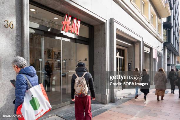 Pedestrians walk past the Swedish multinational clothing design retail company Hennes & Mauritz, H&M store in Madrid.