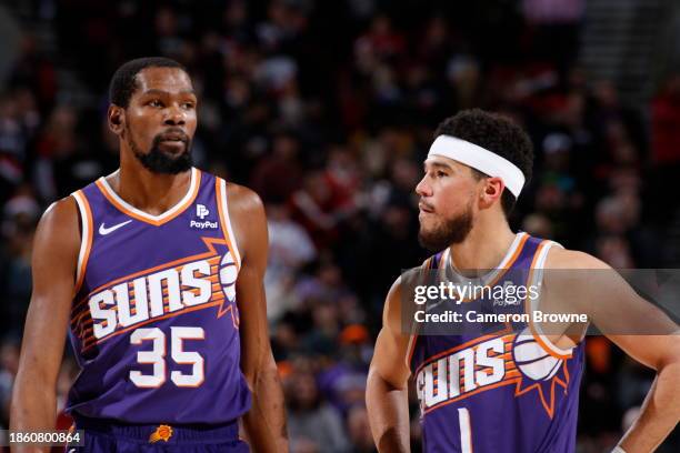 Kevin Durant of the Phoenix Suns and Devin Booker of the Phoenix Suns look on during the game against the Portland Trail Blazers on December 19, 2023...