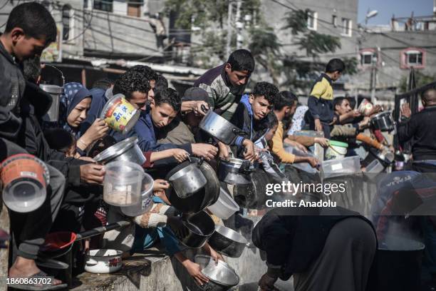 Palestinians receive food and humanitarian aid as Israeli airstrikes continue in Rafah, Gaza on December 19, 2023.