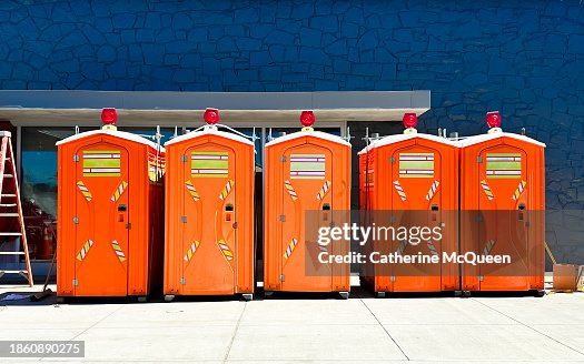 economic growth: row of bright orange portable toilets at construction site