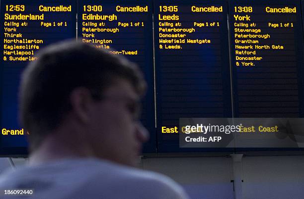 Passenger stands in front of the destination boards showing cancelled trains at Kings Cross train station on October 28 following a strong storm....