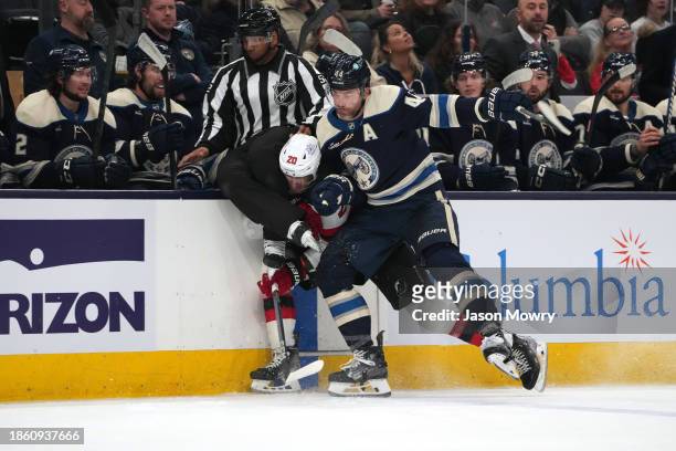Erik Gudbranson of the Columbus Blue Jackets hits Michael McLeod of the New Jersey Devils into the boards and into linesman Shandor Alphonso during...