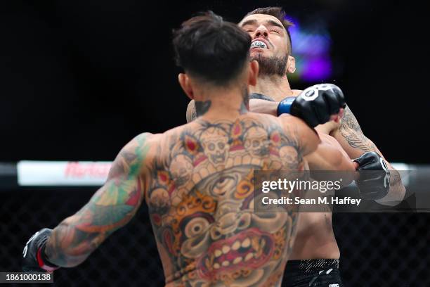 Andre Fili of the United States punches Lucas Almeida of Brazil in a featherweight fight during the UFC 296: Edwards vs. Covington event at T-Mobile...