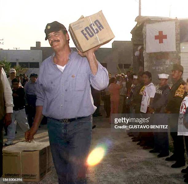 The Mexican President Vicente Fox helps load off aid supplies from a truck for the victims that Hurricane Isidore left, in the state of Campeche,...