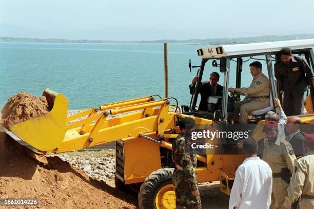 Pakistani President General Pervez Musharraf drives a shovel during the ground-breaking ceremony of Mangla Dam Raising Project at Mangla, some 100...