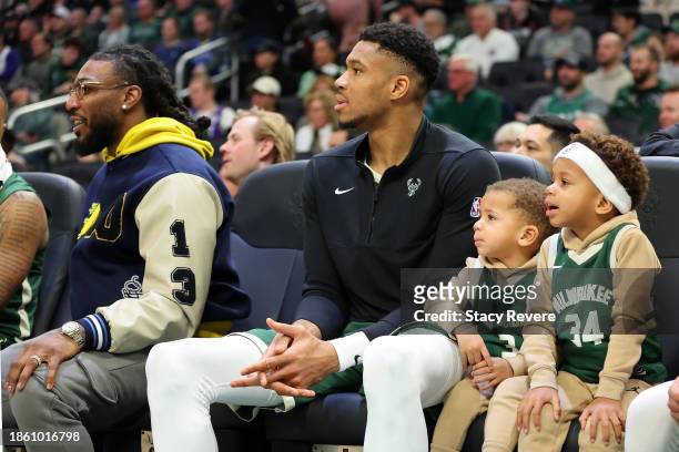 Giannis Antetokounmpo of the Milwaukee Bucks sits on the bench with his children, Liam and Maverick, during a game against the Detroit Pistons at...