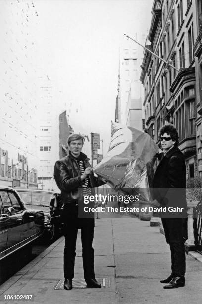 Pop artist Andy Warhol and rock singer, musician, and songwriter Lou Reed pose for a portrait with one of Warhol's iconic pop sculptures, a helium...