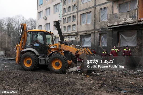 Municipal workers use a bucket loader to remove the rubble outside the residential building at 4A Ostafiia Dashkevycha Street damaged by the debris...