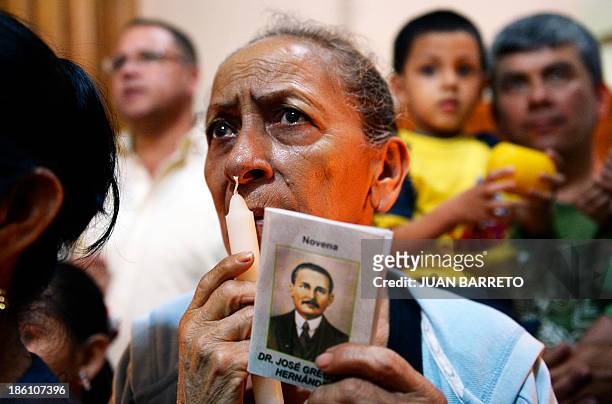 Sofia Miselem A woman holds a card bearing an image of late doctor Jose Gregorio Hernandez, during a mass at the Holy Church of La Candelaria where...