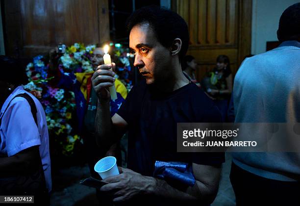 Sofia Miselem A man holds a candle during a mass at the Holy Church of La Candelaria where the remains of late doctor Jose Gregorio Hernandez are...
