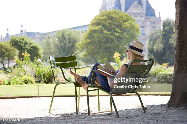 woman sitting in park reading a book - mujer leyendo libro en el parque fotografías e imágenes de stock